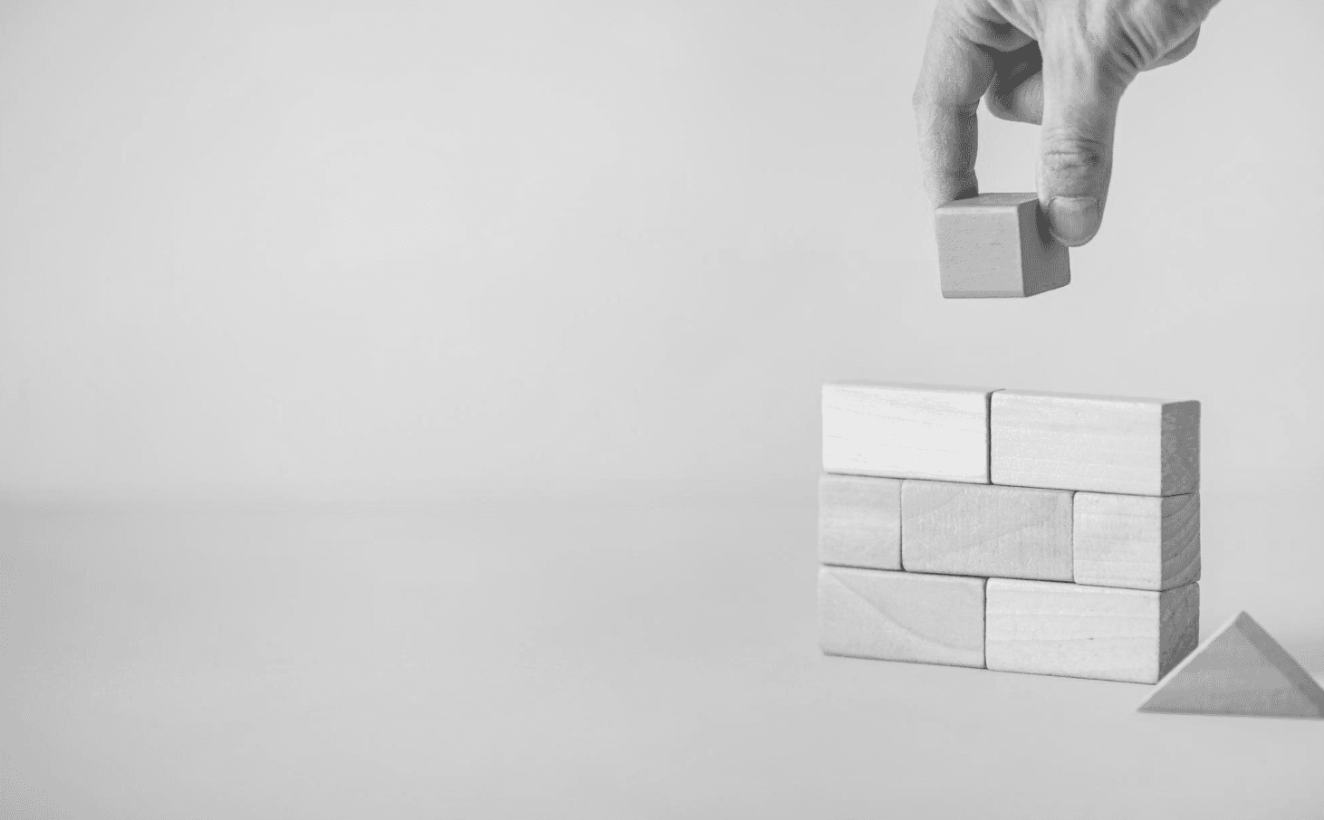 Hand placing a block to complete a structure